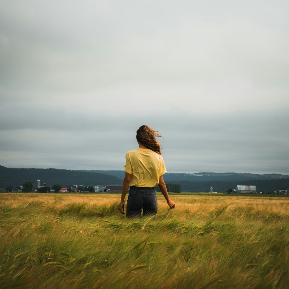 Donna in vestito marrone in piedi sul campo di erba verde durante il giorno