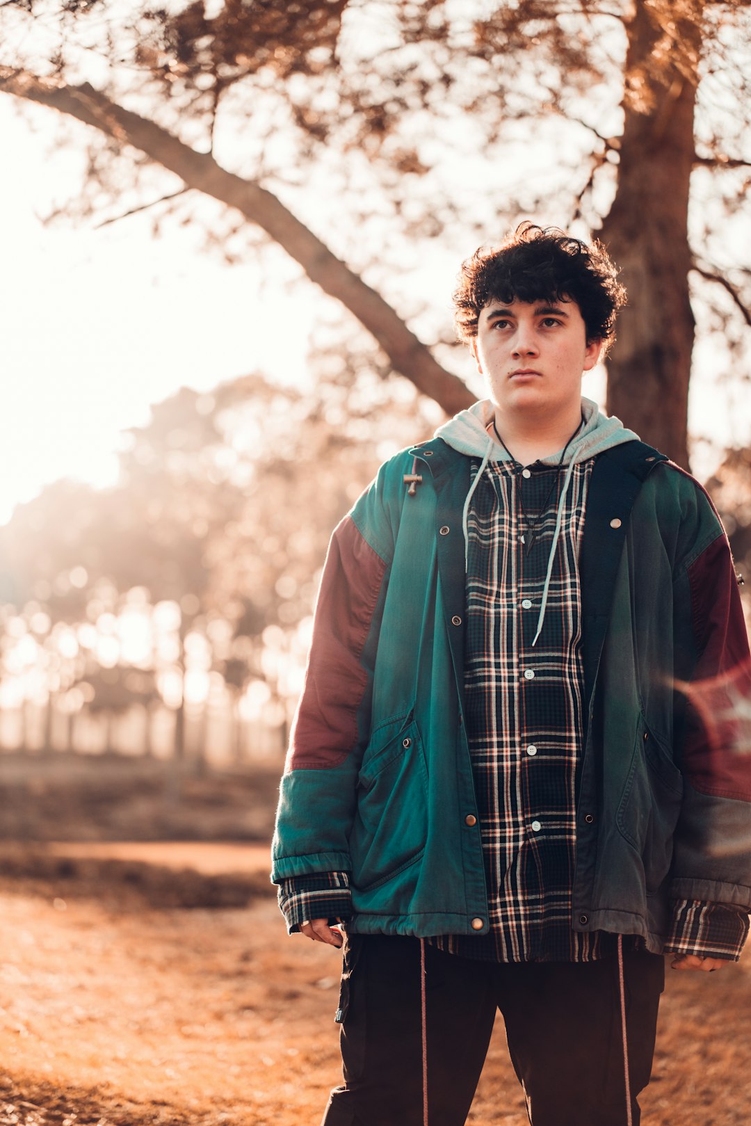 man in blue and black jacket standing near trees during daytime