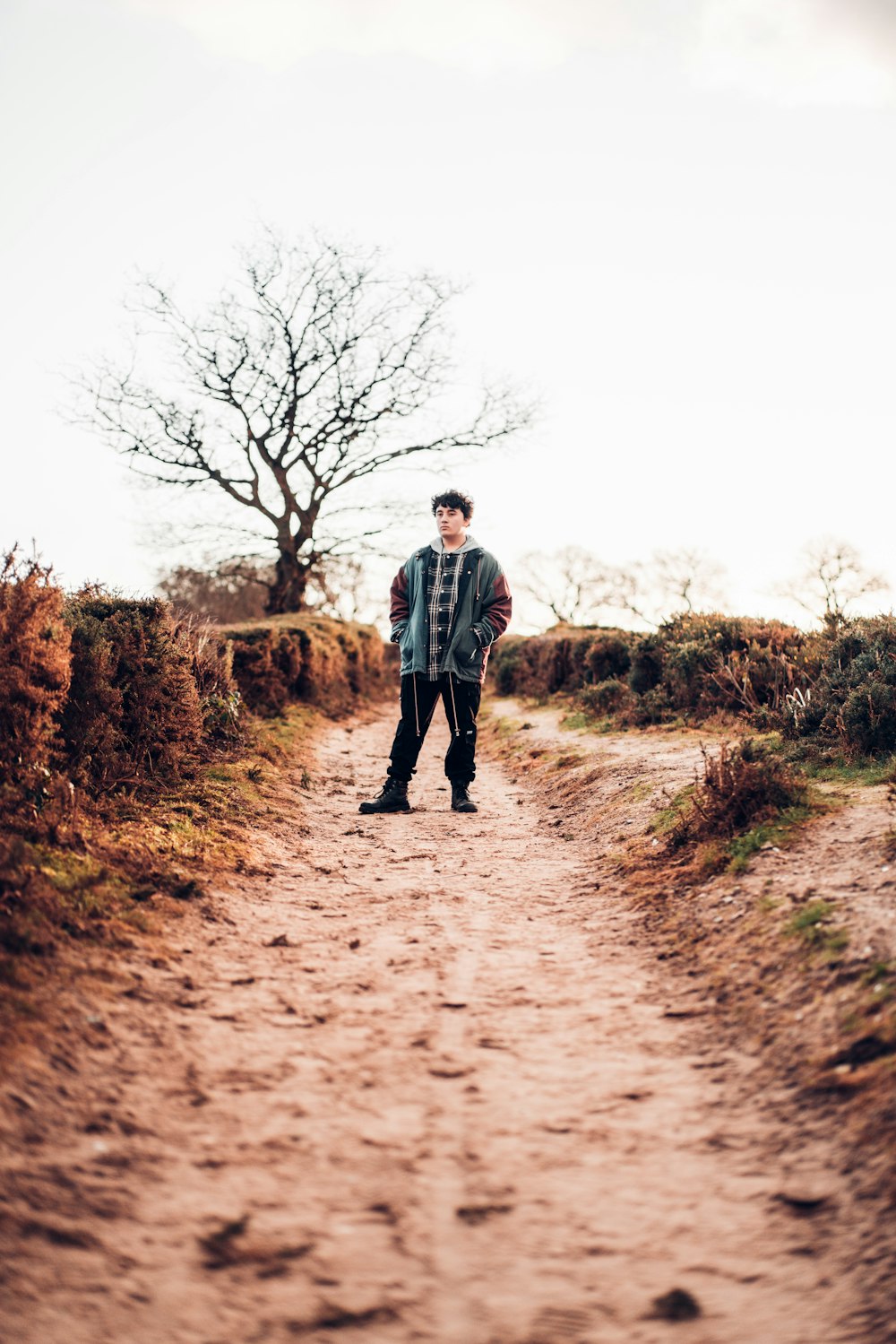 man in grey jacket walking on dirt road during daytime