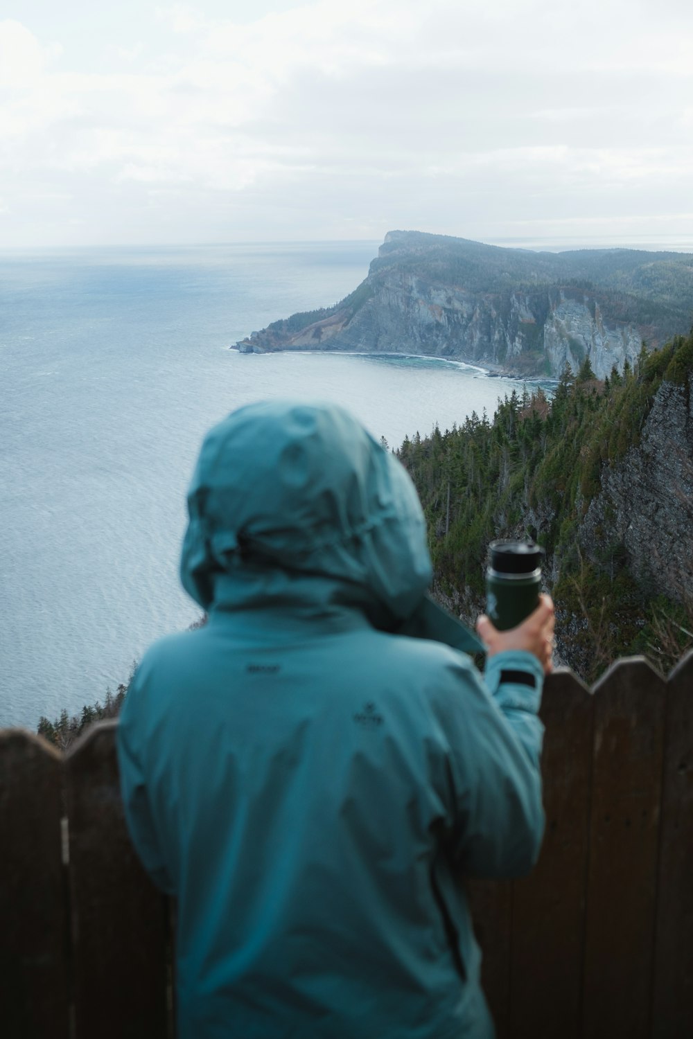 Person in blauem Kapuzenpullover fotografiert tagsüber das Meer