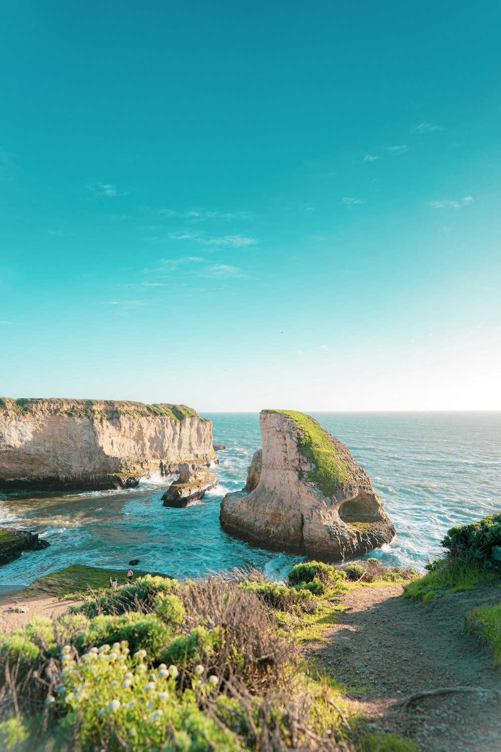 brown rock formation on sea under blue sky during daytime