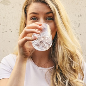 woman in white crew neck shirt drinking water