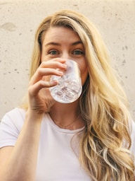 woman in white crew neck shirt drinking water