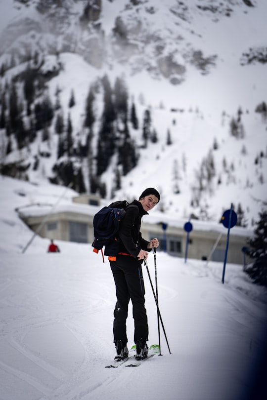 man in black jacket and black pants holding ski poles on snow covered ground during daytime in Schlick Austria