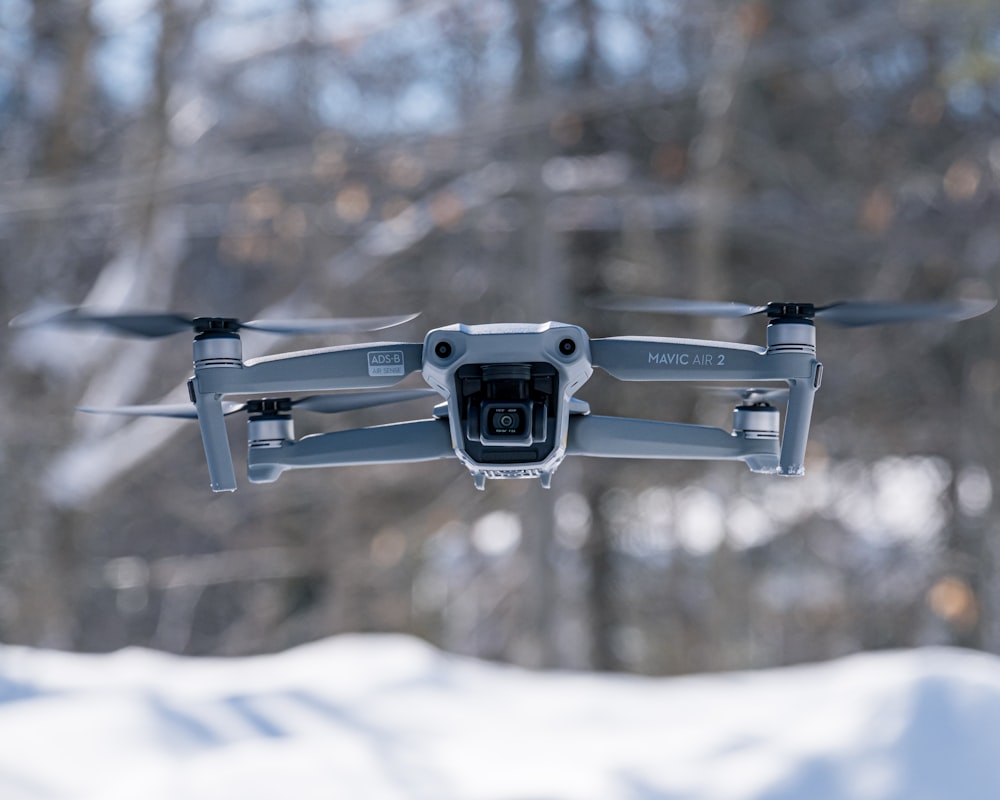 Schwarze Drohne, die tagsüber über schneebedecktes Gelände fliegt