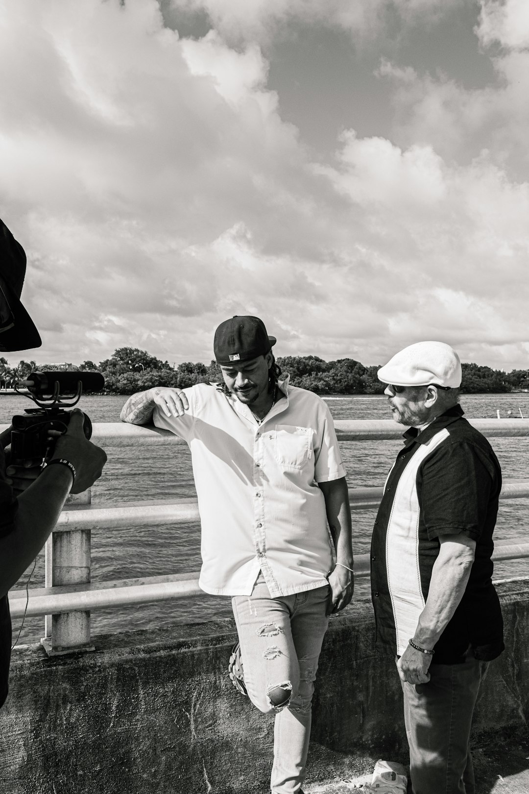 2 men in white dress shirt and black vest standing on wooden fence during daytime