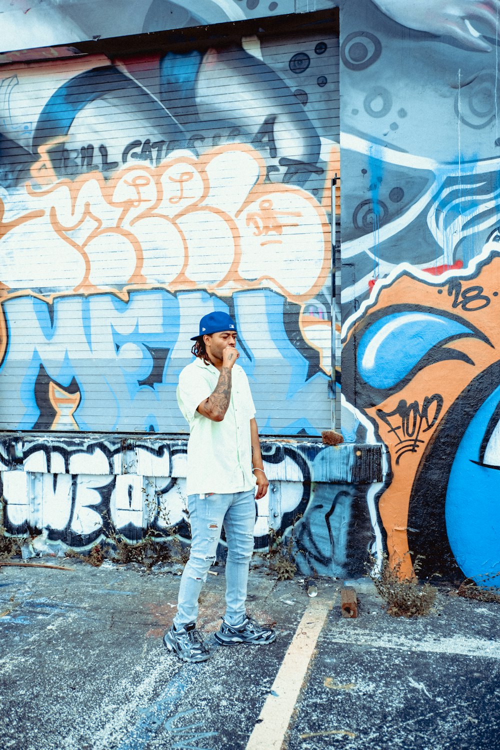 woman in white long sleeve shirt and blue denim jeans standing beside wall with graffiti