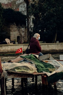 person in red jacket sitting on brown wooden boat during daytime