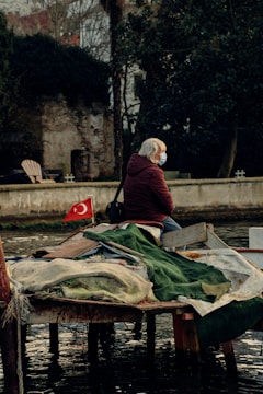 person in red jacket sitting on brown wooden boat during daytime
