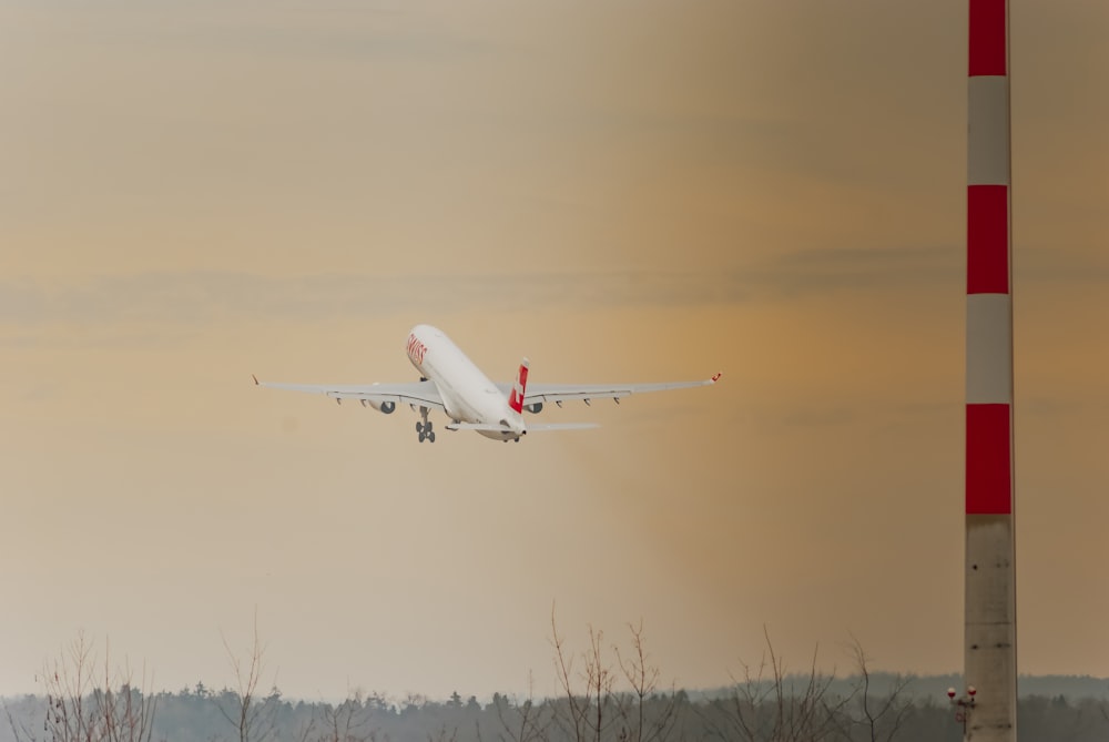 Avión de pasajeros blanco y rojo volando durante el día