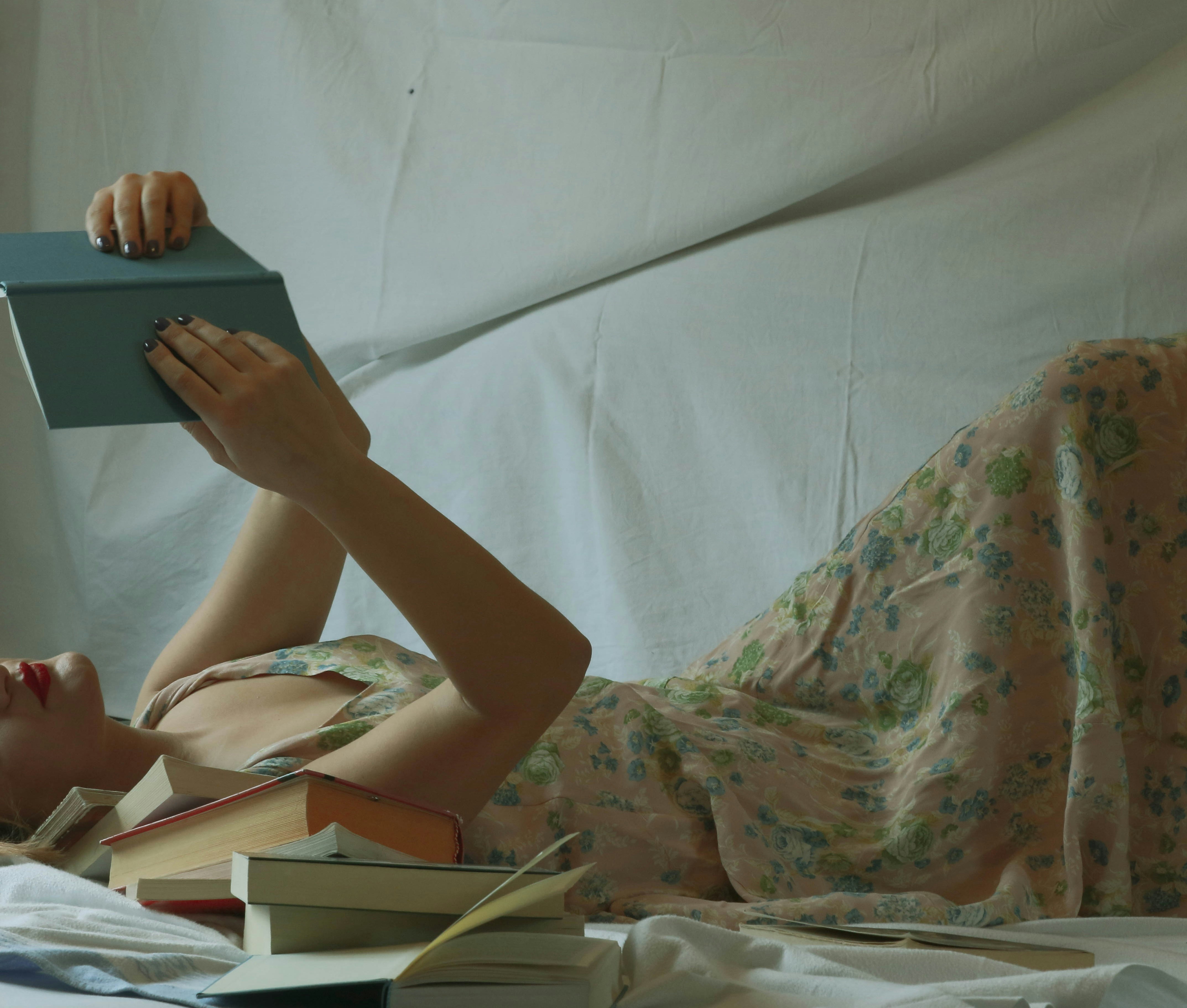 woman in white and green floral dress lying on bed