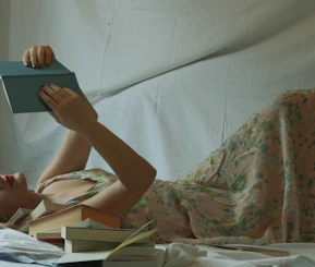 woman in white and green floral dress lying on bed