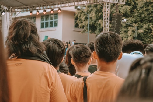 people in orange shirt standing near building during daytime