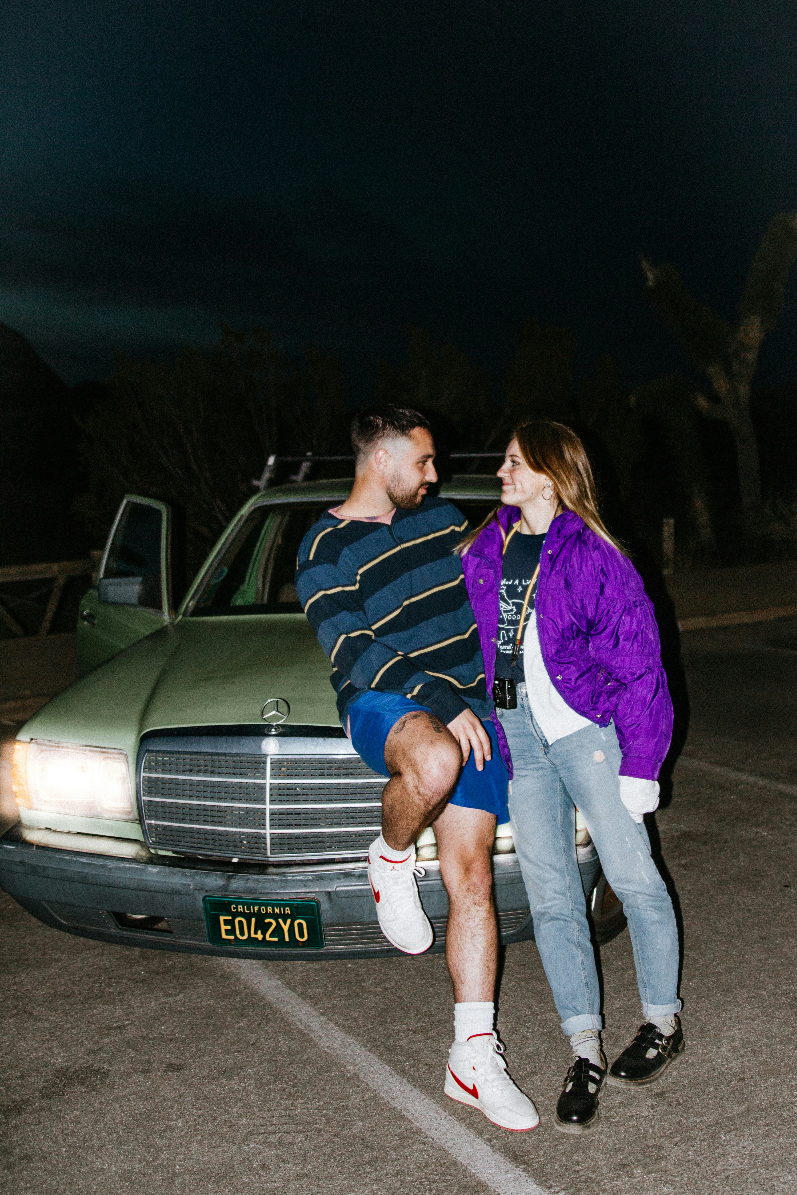 man and woman standing beside white car during night time