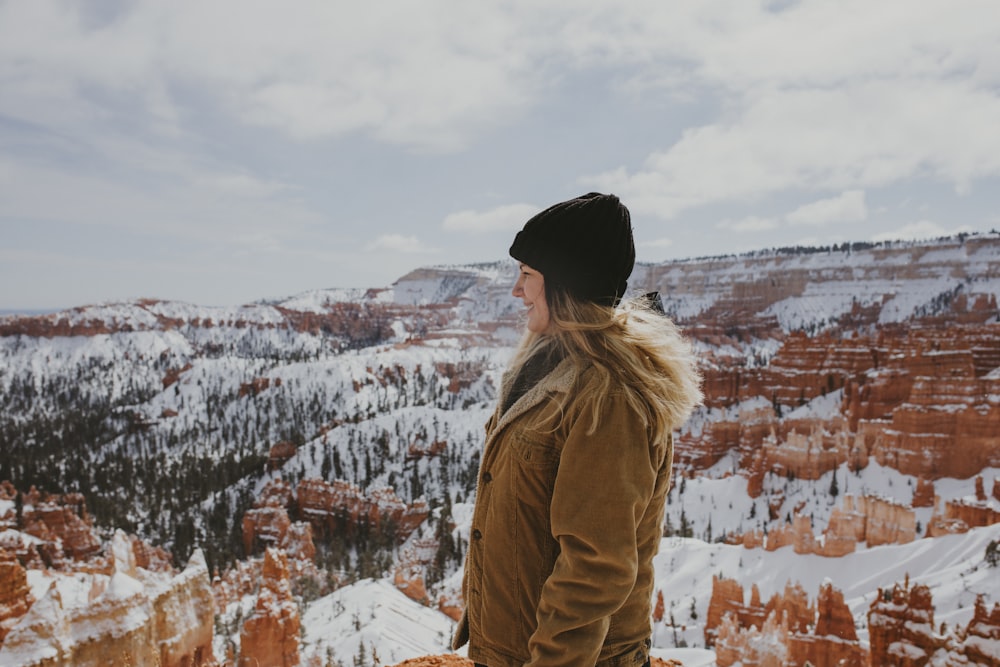 woman in brown coat standing on snow covered ground during daytime