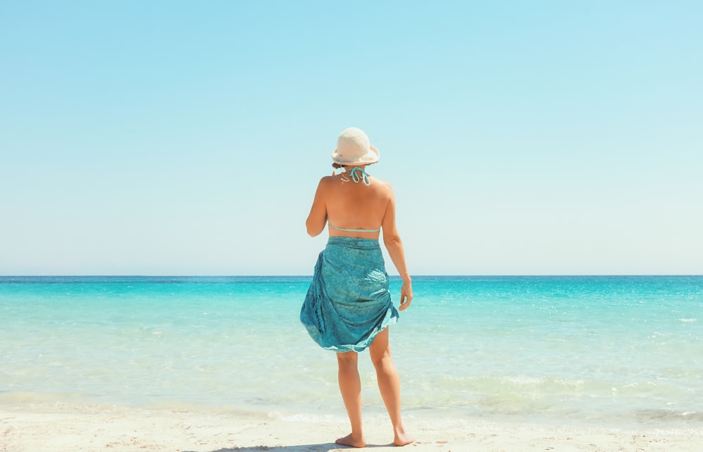 昼間の浜辺に立つ青いスカートの女性