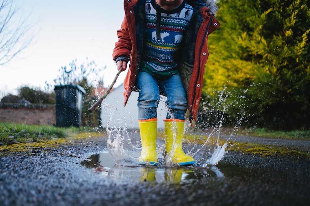 Hombre con chaqueta roja y jeans de mezclilla azules corriendo en el agua