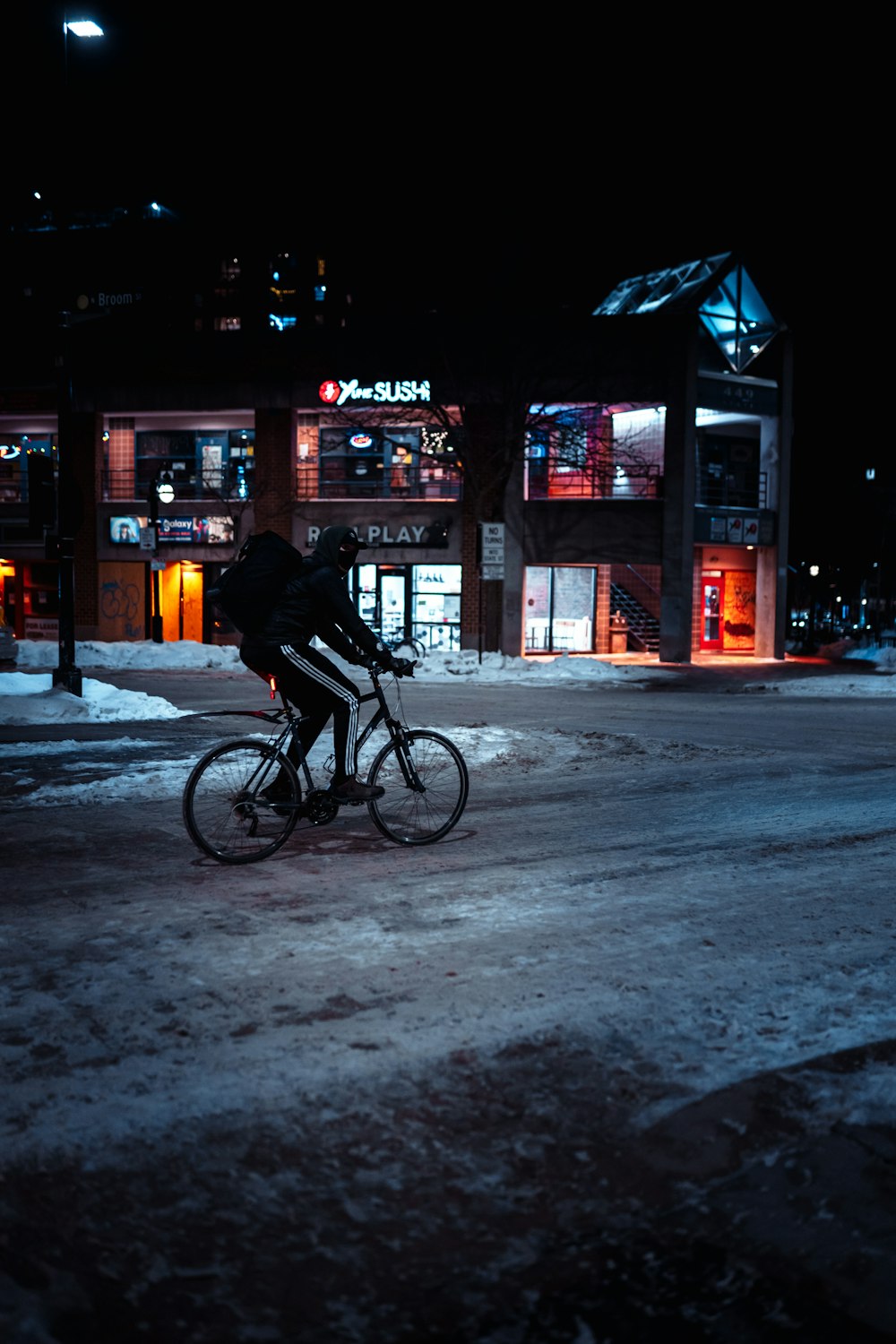 man in black jacket riding bicycle on road during nighttime