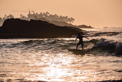 silhouette of person surfing on sea during sunset