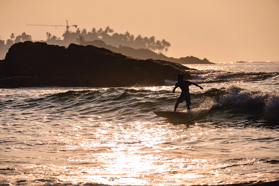 A surfer riding a wave at sunset off Sri Lanka's coast