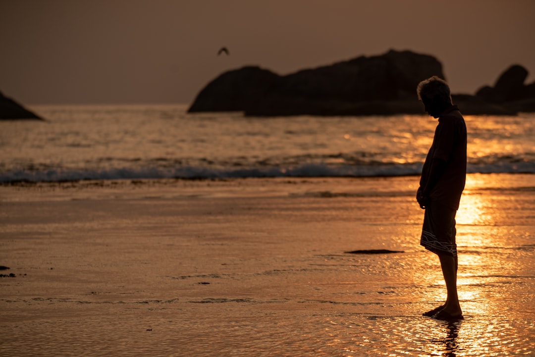 person in black jacket walking on beach during daytime