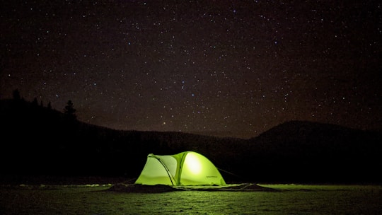 A warm, inviting emergency tent glowing softly under the starry night in the Kedarnath region.