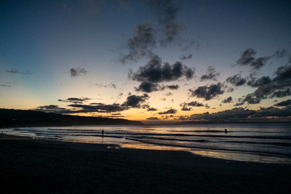 silhouette di persone sulla spiaggia durante il tramonto