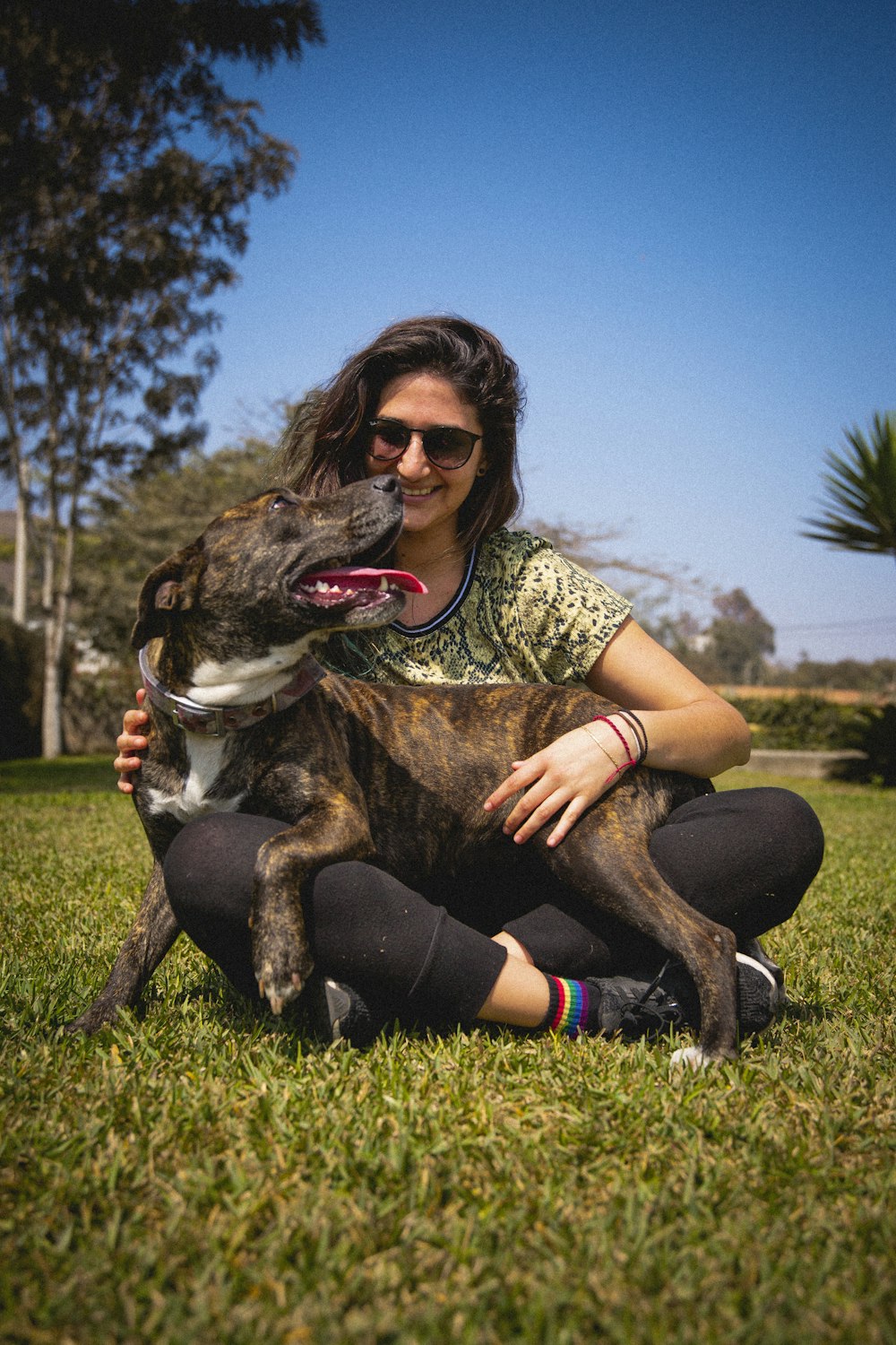 a woman sitting in the grass with her dog