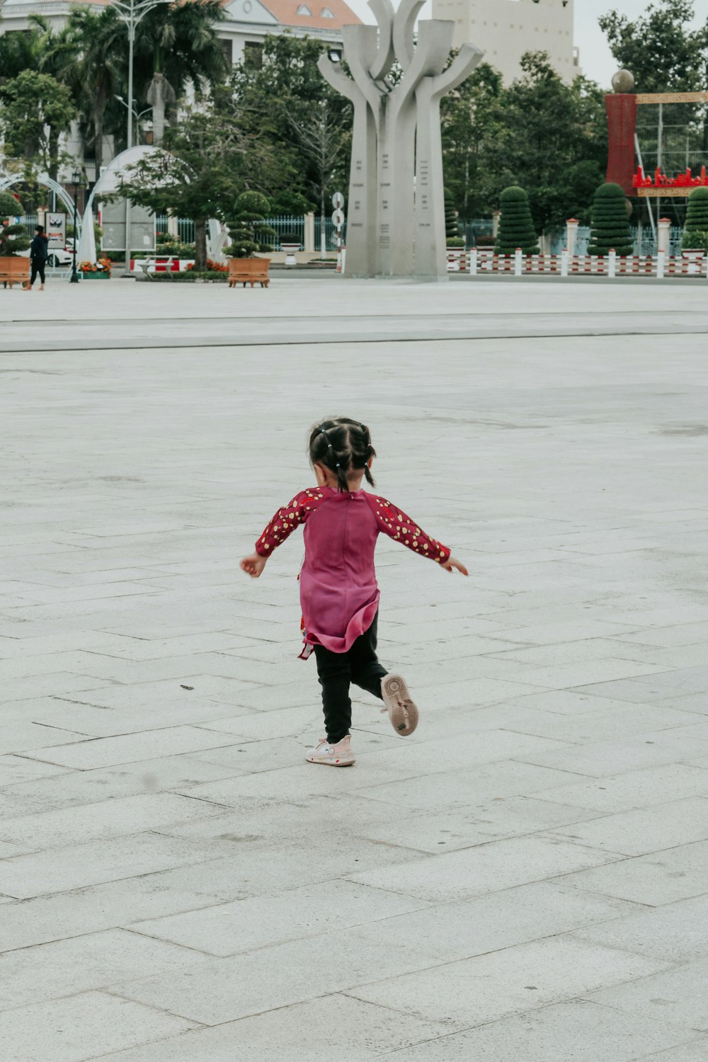 girl in pink jacket and black pants running on white concrete floor during daytime