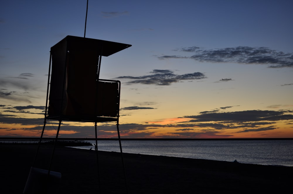 silhouette of lifeguard tower on beach during sunset