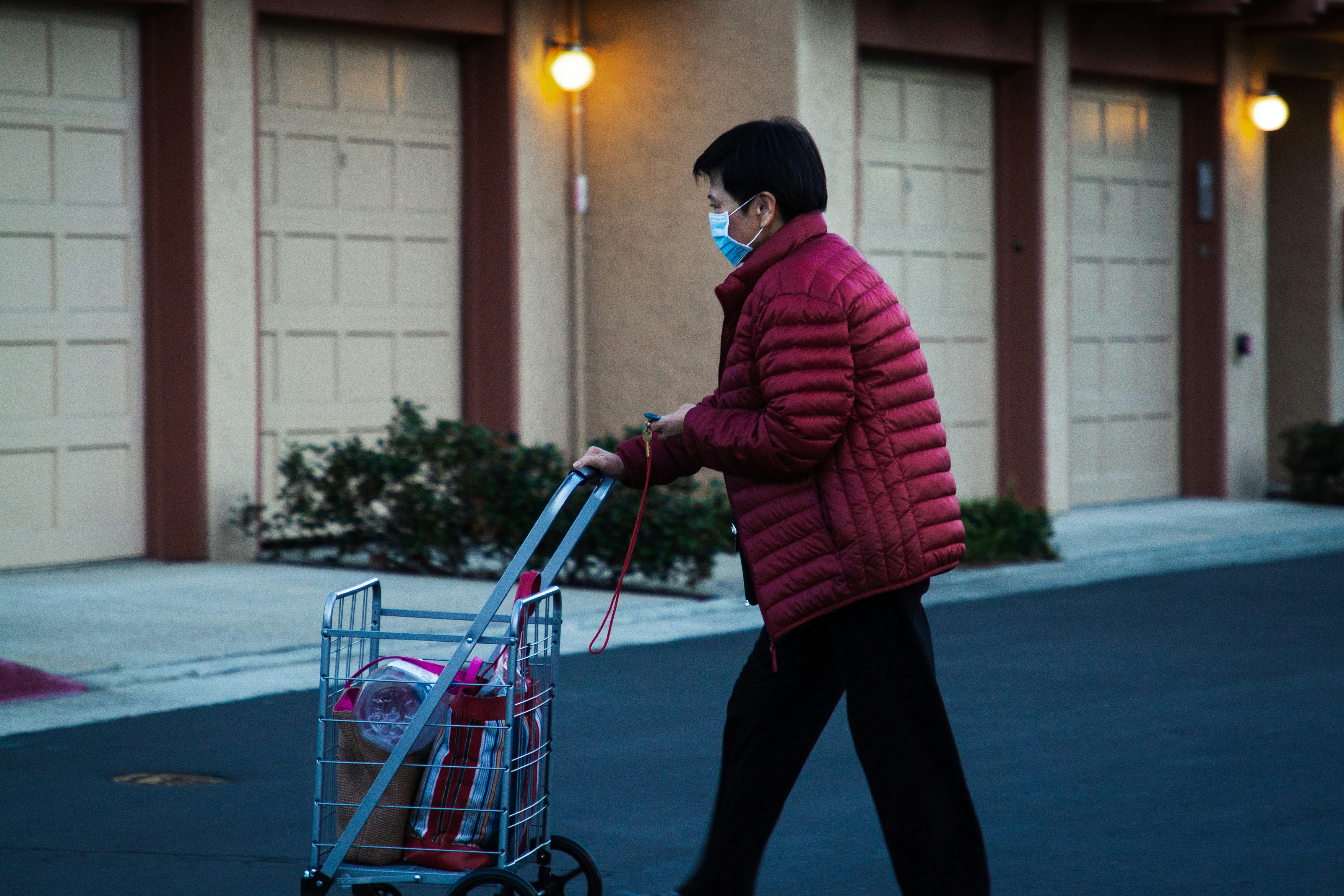 man in red and black striped hoodie and black pants riding on red and gray shopping