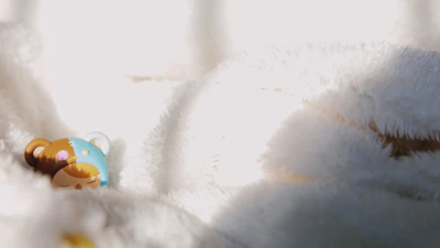 A colorful handmade wooden toy bear sitting on a cozy knitted blanket.