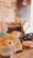 A cozy shop display featuring plush toys, with one prominently wearing a beige bow. Surrounding items include accessories and decorative pieces, with signs displaying prices. The warm lighting and lace tablecloth add a quaint and inviting atmosphere.