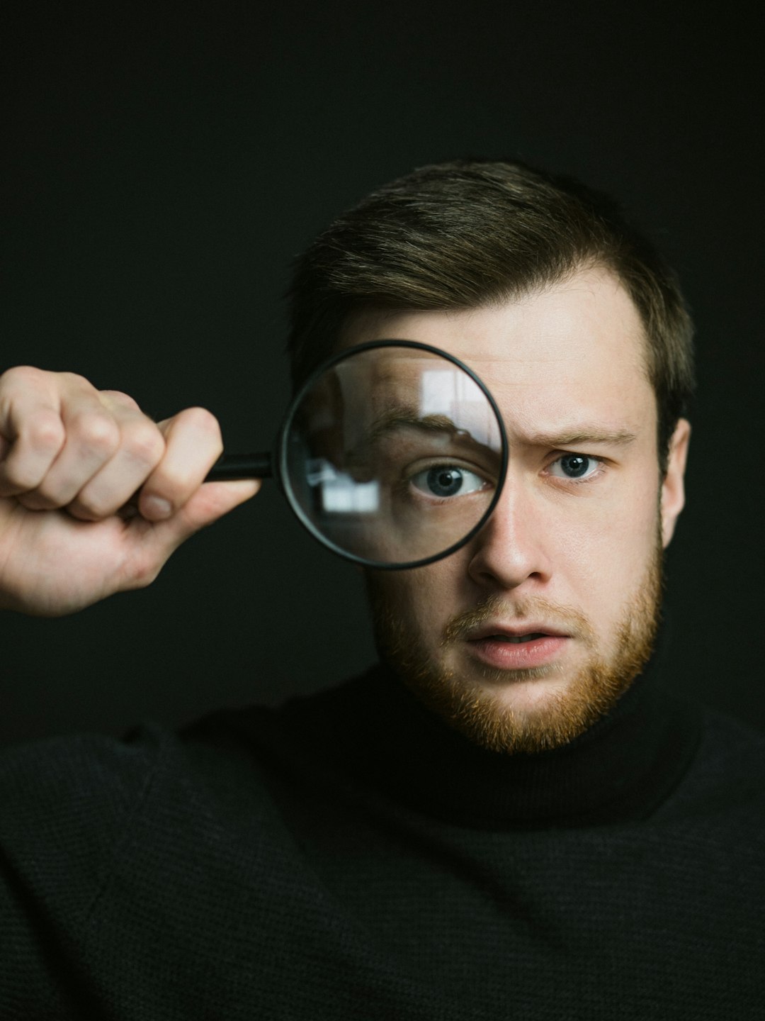 man in black crew neck shirt holding magnifying glass
