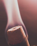 Close-up of a traditional Indian dhoop stick burning gently with curling smoke against a warm saffron background.