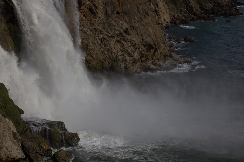 water falls on brown rocky mountain during daytime