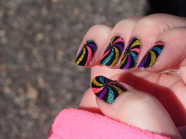 Bright neon nails with a mix of geometric patterns and shimmering glitter highlights.