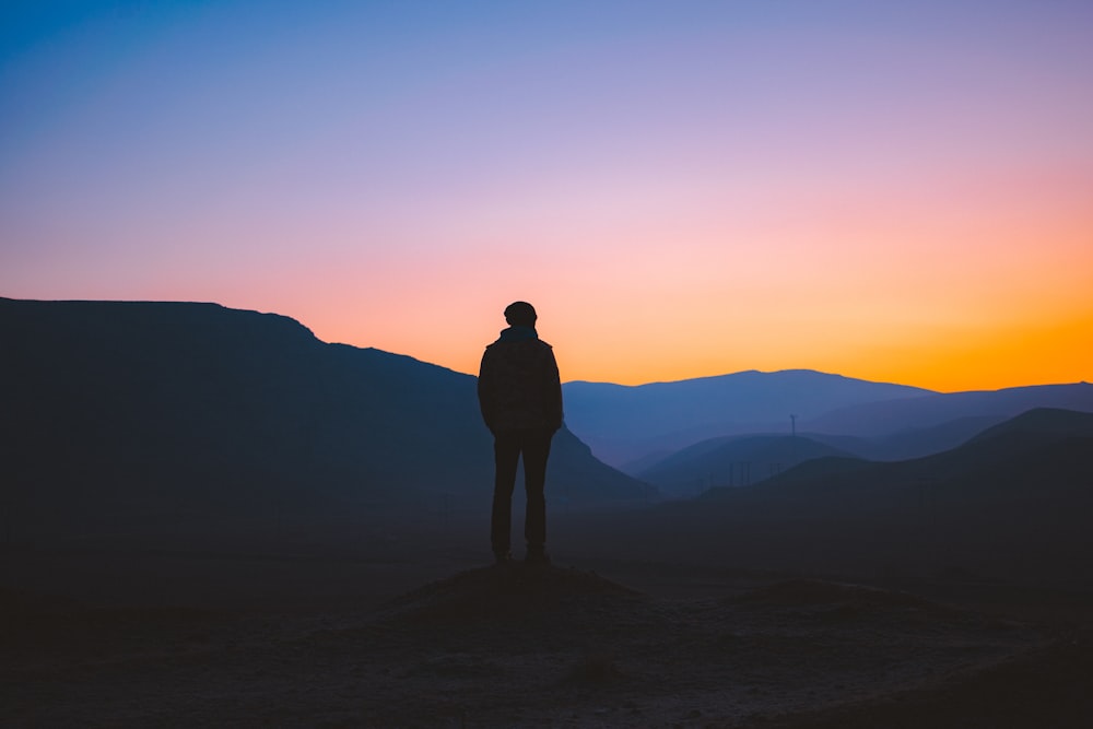 일몰 동안 산에 서 있는 남자의 실루엣