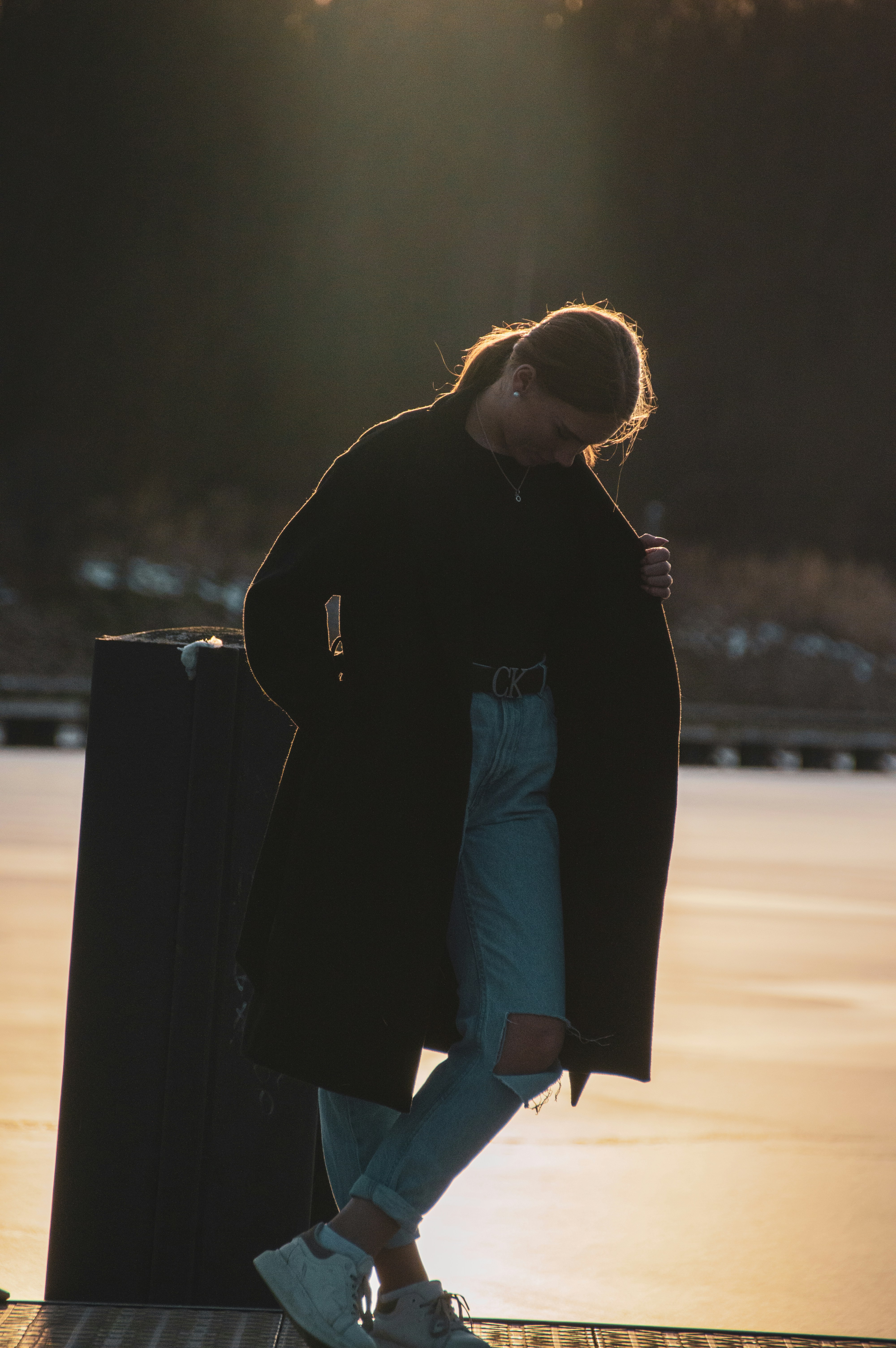 woman in black coat standing on road during daytime