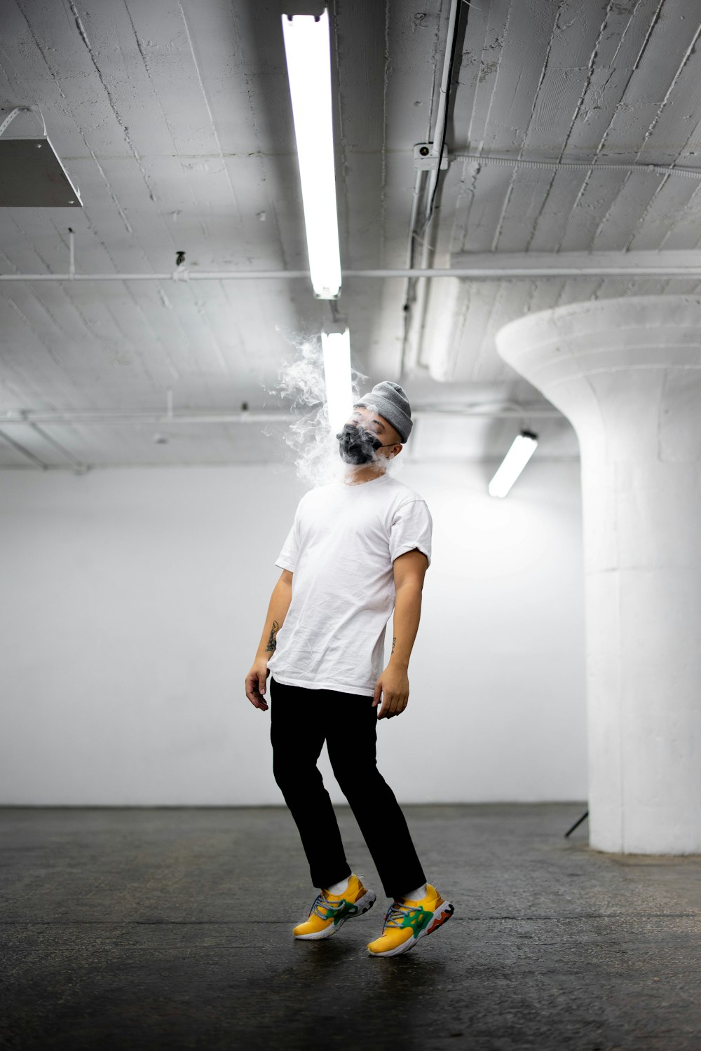 man in white crew neck t-shirt and black pants standing on gray floor
