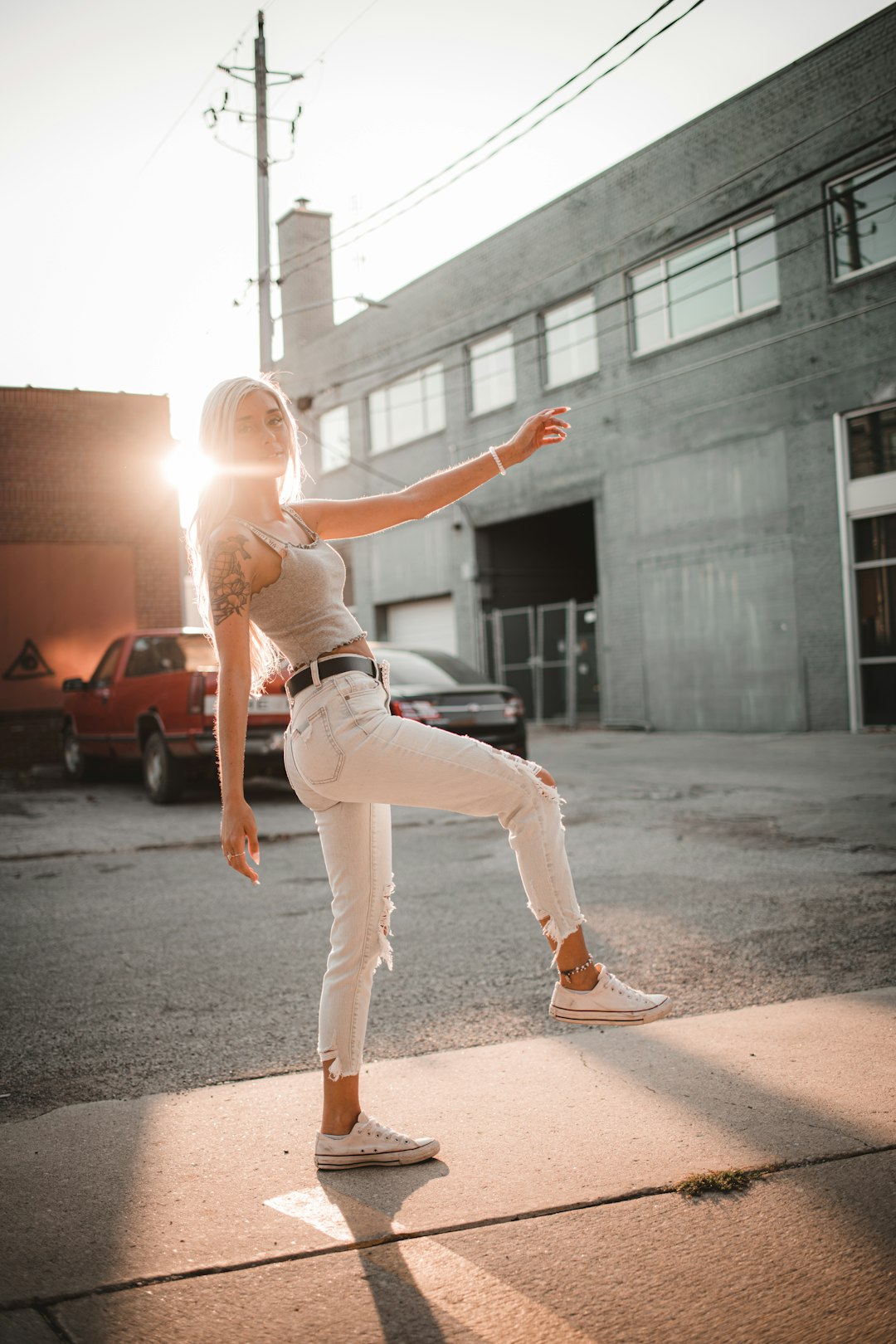 woman in white tank top and white pants running on gray asphalt road during daytime