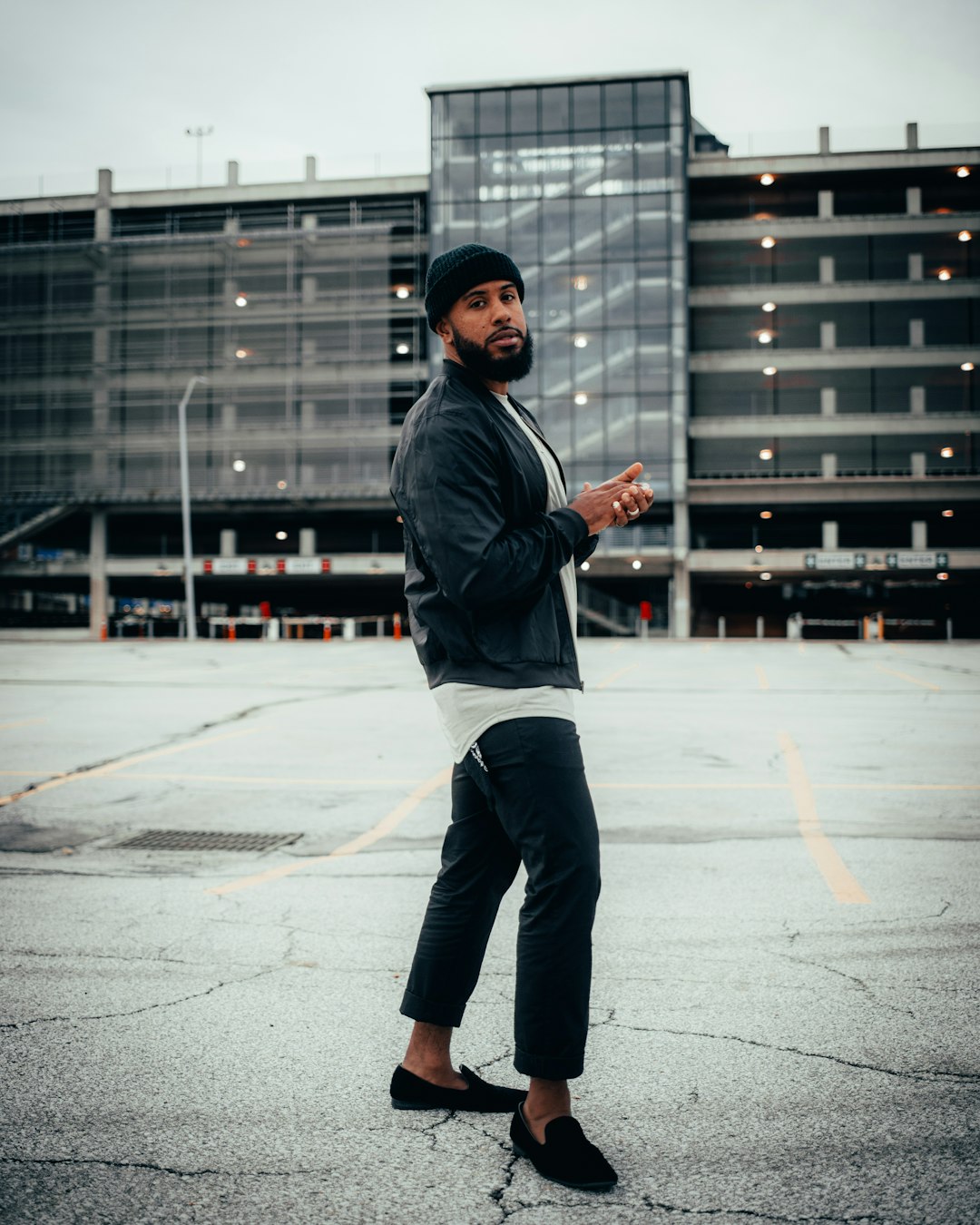 man in black jacket and black pants standing on gray concrete floor