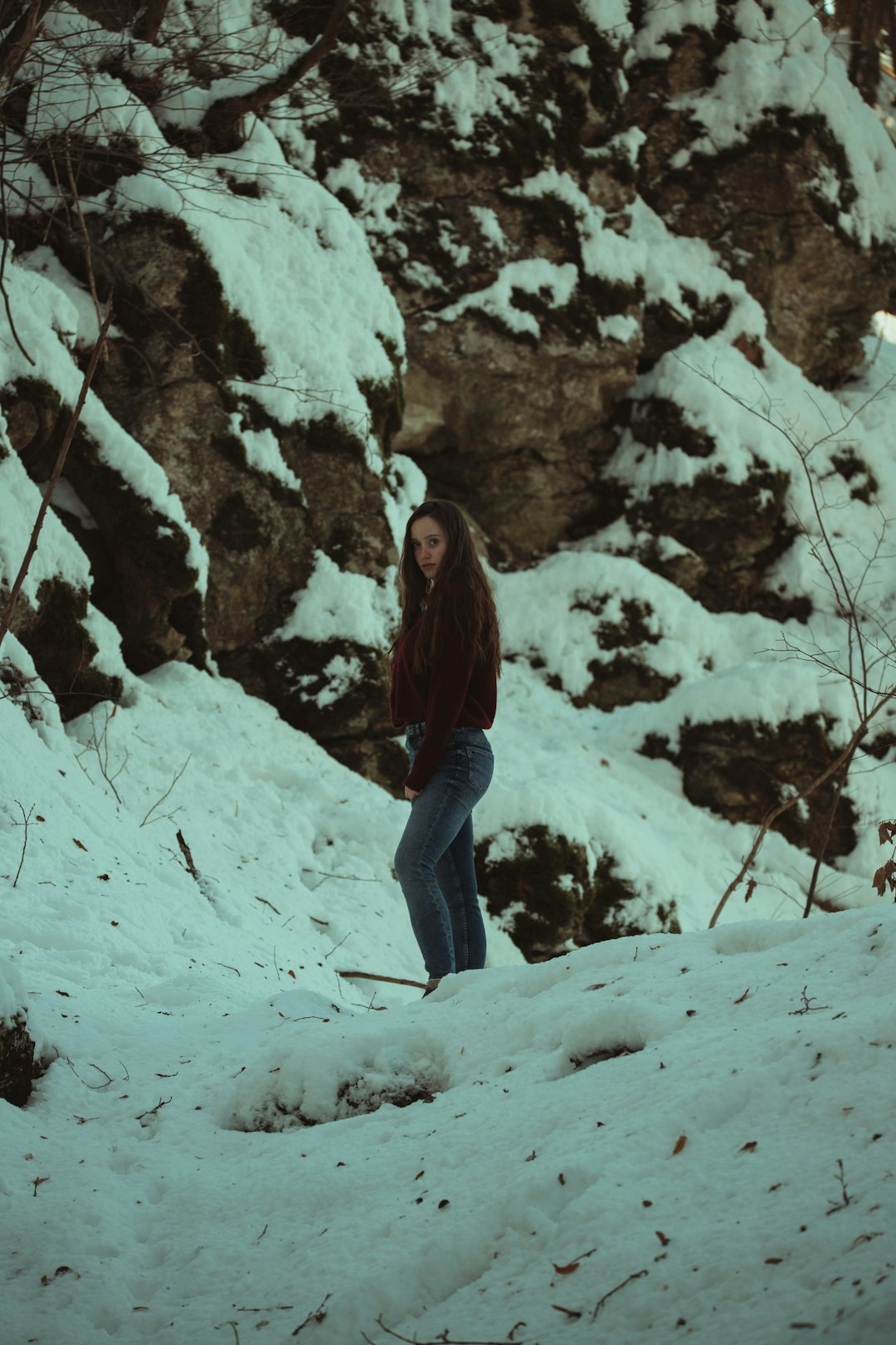 woman in black jacket and blue denim jeans standing on snow covered ground