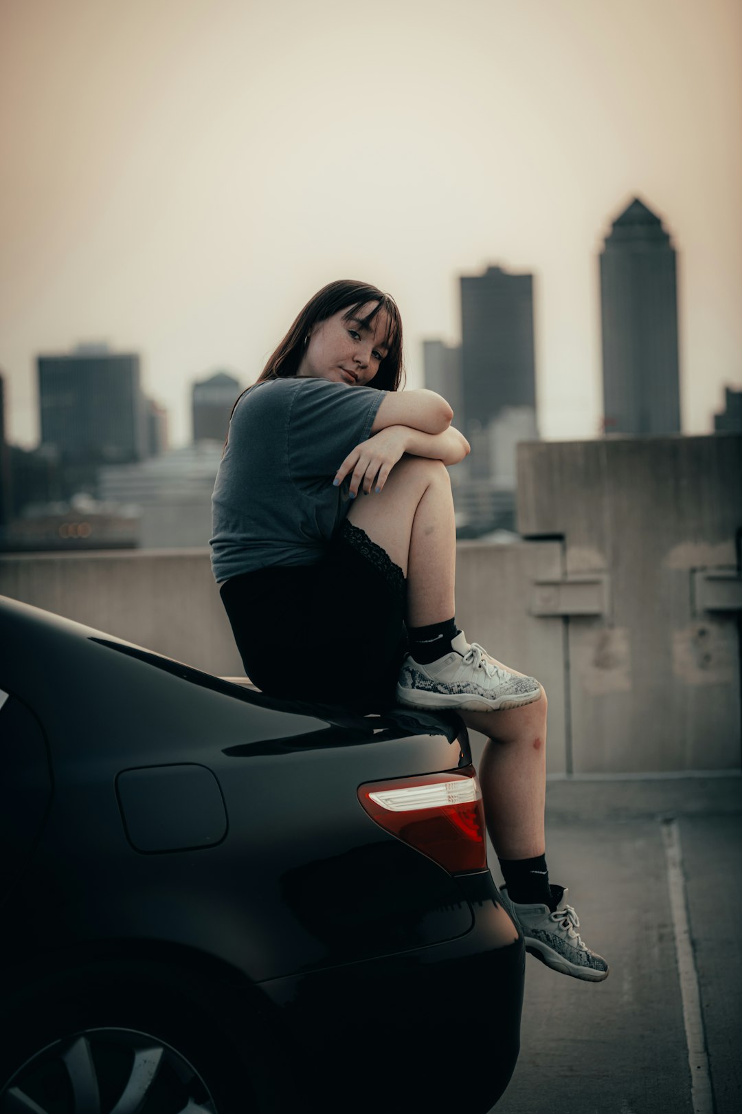 woman in black long sleeve shirt and white denim shorts sitting on black car