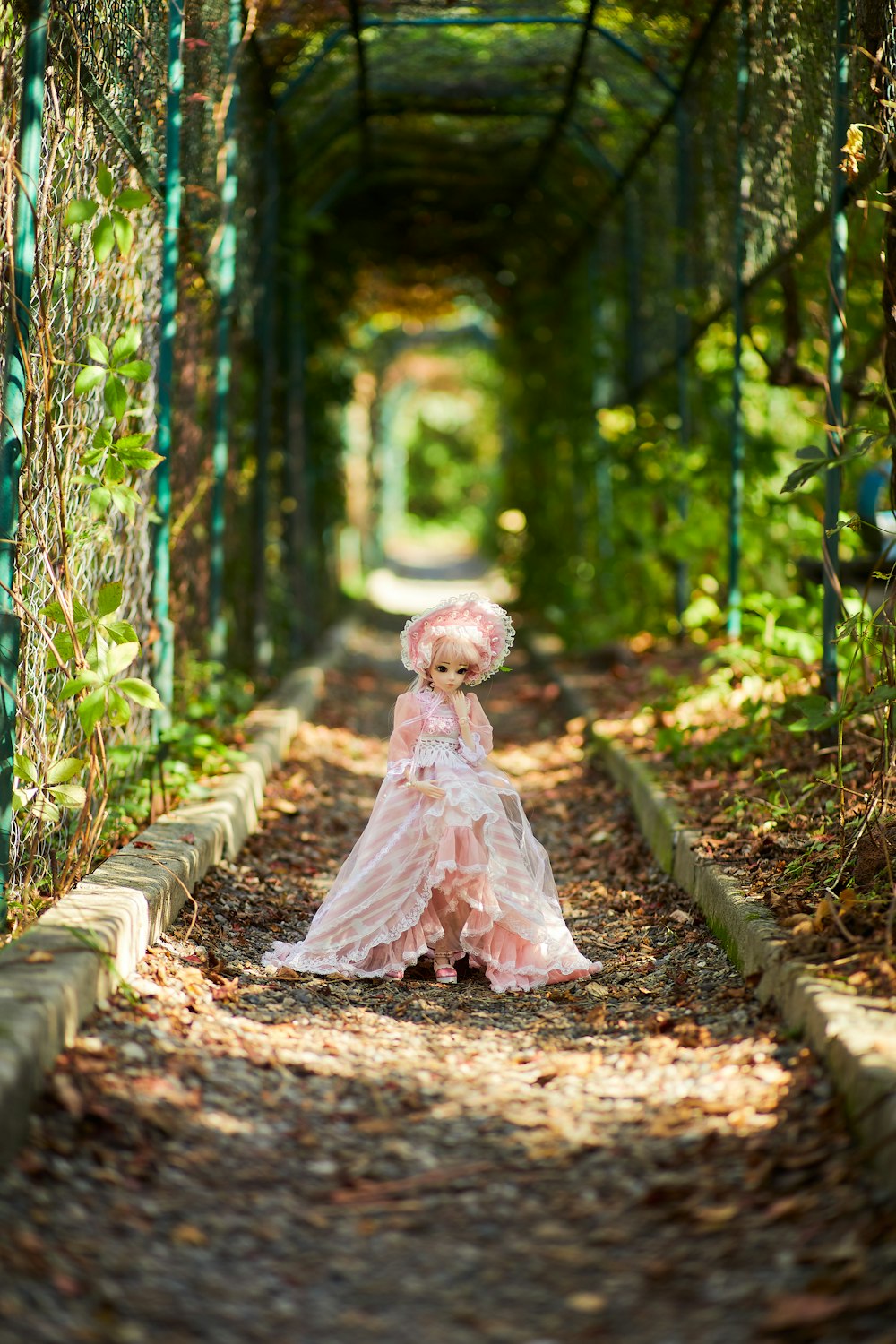 昼間、緑の木々に囲まれた茶色の小道を歩く白いドレスの少女