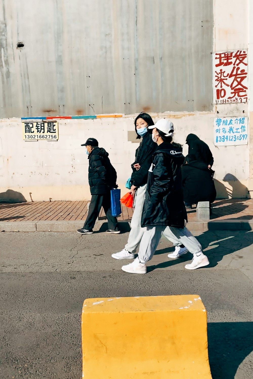 man in black jacket walking on sidewalk during daytime