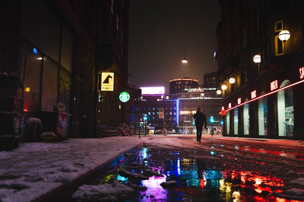 man in black jacket walking on street during night time