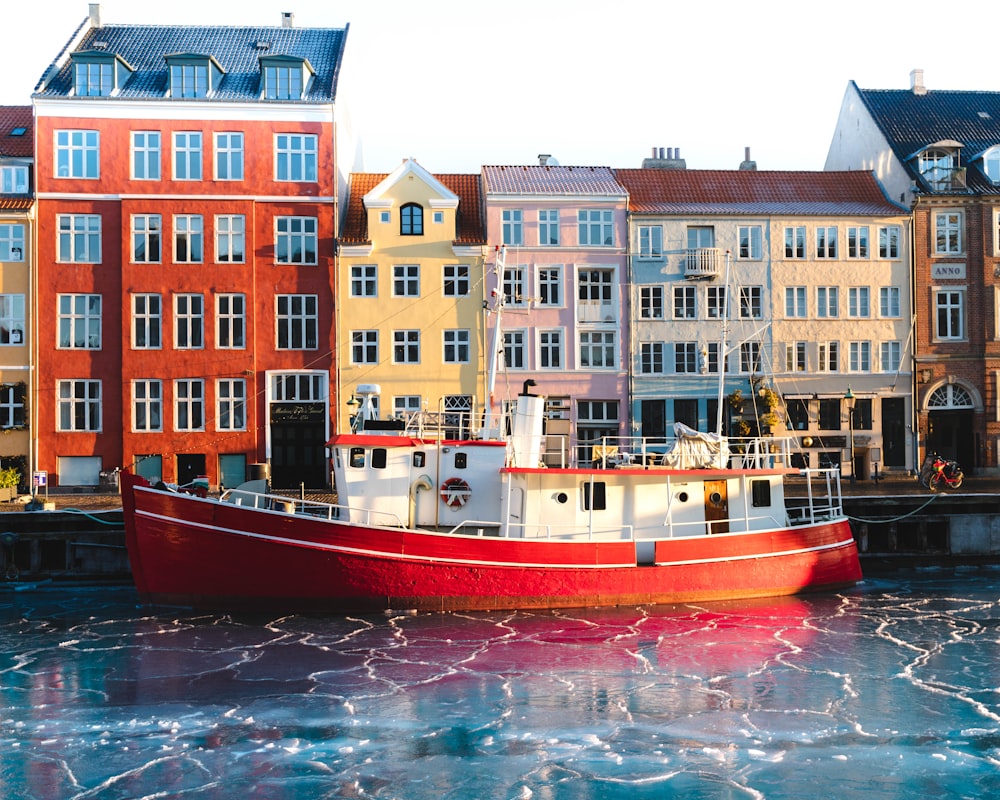 red and white boat on water near concrete building during daytime