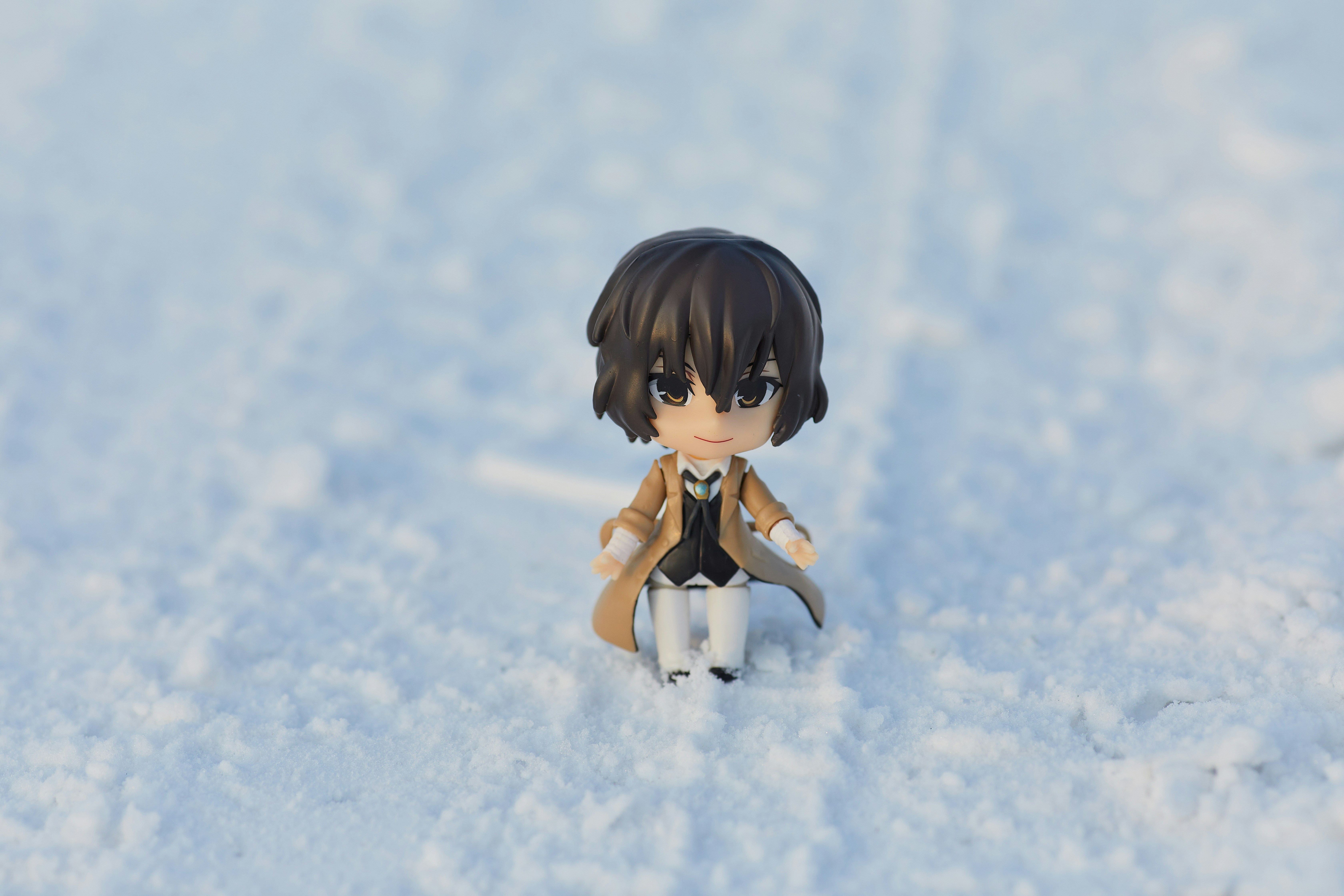 Miniature doll (Dazai) on white snow. Stylish anime doll background for website and design