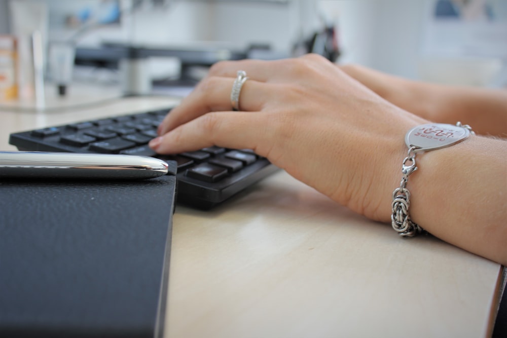 Persona que lleva anillo plateado con teclado de computadora negro